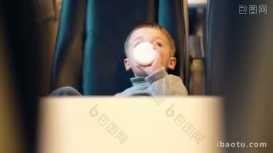快<strong>车上</strong>的小男孩从两个座位之间的瓶子里喝牛奶
